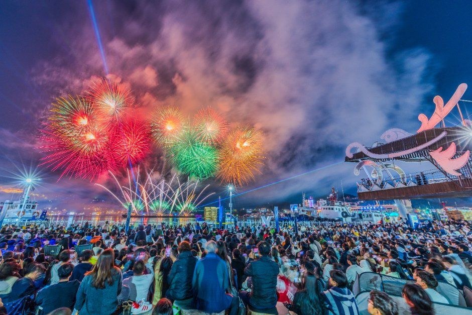 밤하늘에 초록과 빨강 불꽃이 터지고 아래로 관람객들이 가득 모인 여수 불꽃축제 현장